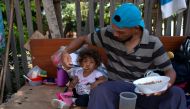 FILE PHOTO: In this file photo taken on August 23, 2018 a Venezuelan man and his daughter eat a meal on the side of a road in Boa Vista, Roraima state, Brazil. / AFP / Mauro Pimentel