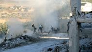 Syrians use dirt to put out a fire at the scene of a reported air strike in the district of Jisr al-Shughur, in the Idlib province, on September 4, 2018. AFP / Zein Al Rifai