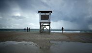 People stand near a lifeguard stand as Hurricane Florence approaches, on September 11, 2018 in Wrightsville Beach, United States. Mark Wilson/AFP