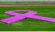 In this file photo taken on October 8, 2017 people gather around a pink ribbon, made up of eight thousand pink footballs, during an event to raise awarness on breast cancer at the Sport City Stadium in Beirut.  AFP / Anwar Amro