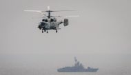 A military helicopter flies over a Russian battleship during the Vostok-2018 (East-2018) military drills at Klerka training ground on the Sea of Japan coast, outside the town of Slavyanka, some 100km south of Vladivostok, on September 15, 2018. / AFP / Ml
