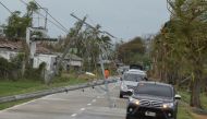 Vehicles commute past electric posts toppled by strong winds from Super Typhoon Mangkhut in Baggao, Cagayan province on September 15, 2018.  AFP / TED ALJIBE