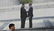A man walks past a giant banner showing a picture of the summit handshake between South Korean President Moon Jae-in and North Korean leader Kim Jong Un, at Seoul City Hall on September 13, 2018. AFP / Jung Yeon-je