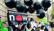 Environmental activists hold black balloons, posters and banners, reading for example 