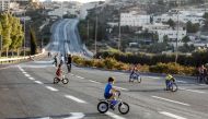 Palestinian youths ride bicycles along an empty street in east Jerusalem on September 19, 2018 as Jews mark Yom Kippur, the holiest day of the Jewish year, and abstain from driving.  AFP / Ahmad Gharabli
 