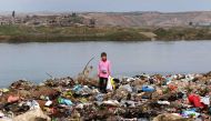 An Iraqi girl stands amid garbage on the banks of the Tigris River in the village of Wana, some 10 kms south of the Mosul Dam near the city of Mosul on March 3, 2016. AFP/Safin Hamed