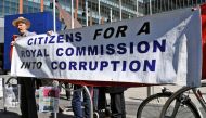 People hold a banner outside the Banking Royal Commission being held in Melbourne on September 26, 2018. / AFP / William WEST