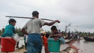 A Rohingya refugee carries two children in buckets as they arrive in Bangladesh at Shah Porir Dwip in Teknaf on September 9, 2017, as they flee violence in neighbouring Myanmar (AFP/Emrul Kamal) 