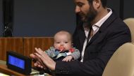 Clarke Gayford (C) claps holding his daughter Neve Te Aroha Ardern Gayford, as his partner Jacinda Ardern, Prime Minister of New Zealand speaks during the Nelson Mandela Peace Summit September 24, 2018 in New York. AFP / Don EMMERT 