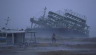 A person reacts to the weather as ship washed ashore caused by Typhoon Trami is seen at a port in Yonabaru, on the southern island of Okinawa, Japan, in this photo taken by Kyodo September 29, 2018. Kyodo via REUTERS
