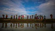 FILE PHOTO: Rohingya refugees are reflected in rainwater along an embankment next to paddy fields after fleeing from Myanmar into Palang Khali, near Cox's Bazar, Bangladesh November 2, 2017. REUTERS/Hannah McKay