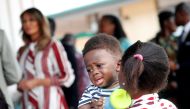 A woman holds a child as U.S. first lady Melania Trump visits a hospital in Accra, Ghana, October 2, 2018. REUTERS/Carlo Allegri