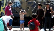 A child washes himself next to a watering hole in the refugees camp at the Greek-FYR of Macedonia border near the village of Idomeni on May 23, 2016. AFP/Sakis Mitrolidis