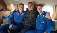 Head of Russian space agency Roscosmos Dmitry Rogozin (C) poses with astronauts Alexey Ovchinin of Russia and Nick Hague of the U.S., who survived the mid-air failure of a Russian rocket, on onboard a plane during a flight to Chkalovsky airport near Star 