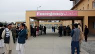 Afghan relatives of victims looks on as they stand in front of a hospital following a bomb attack in Taloqan in northeastern Takhar province on October 13, 2018. AFP / NASEER SADEQ