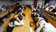 Schoolchildren cover their heads with their hands as they take part in security exercises in the school in the Kiev-controlled village of Sartana, Donetsk region on October 2, 2018. AFP / Aleksey FILIPPOV