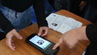  An Afghan Independent Election Commission (IEC) official (L) scans a voter's finger with a biometric device at a polling centre for the country's legislative election in Parwan province on October 20, 2018. / AFP / ABDUL SHAHMIM TANHA 