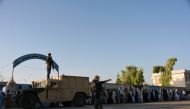 Afghan policemen stand guard as voters wait to cast their votes at a polling centre for the country's legislative election in Kandahar on October 27, 2018. AFP / JAWED TANVEER
 