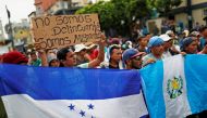 Central Americans, part of a caravan trying to reach the U.S., protest by the border gate as they wait to cross into Mexico and carry on their journey, in Tecun Uman, Guatemala, October 28, 2018. The placard reads 