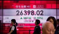 Pedestrians walk past a stocks display board that shows an increase in the Hang Seng Index in Hong Kong on November 2, 2018. / AFP / Anthony WALLACE