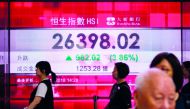 Pedestrians walk past a stocks display board that shows an increase in the Hang Seng Index in Hong Kong on November 2, 2018.  AFP / Anthony Wallace
