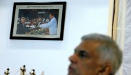 A photograph of Sri Lanka's ousted Prime Minister Ranil Wickremesinghe taking an oath as he was sworn in before President Maithripala Sirisena in 2015, is seen on a wall as Wickremesinghe speaks during an interview with Reuters at the Prime Minister's off