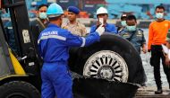 A worker assists his colleague during the lift up of a damaged tyre from the Lion Air flight JT610 jet, at Tanjung Priok port in Jakarta, Indonesia, November 5, 2018. REUTERS/Beawiharta