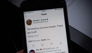 A smartphone shows a tweet by US President Donald Trump saying 