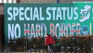 A man walks past a billboard in west Belfast erected by Republican Party Sinn Fein calling for a special status for northern Ireland with respect to Brexit and no hard borders in Ireland on December 08, 2017. AFP / Paul Faith 