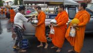 This picture taken on October 23, 2018, shows a devotee giving food offerings to Buddhist monks outside a temple in Bangkok. Romeo Gacad / AFP