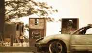 In this file photo taken on November 11, 2018 a burnt car and a gas station remain visible after the 