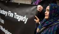Saeeda Khatoon, mother of Aijaz Ahmed, who died in a fire in a Pakistani textile factory, and supporters of the civil trial against the textile discounter KiK, then the factory's main customer, hold a banner in front of the regional court in Dortmund on N