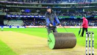 A photo taken on November 23, 2018 shows Melbourne Cricket Ground (MCG) curator Matt Page (L) rolling the pitch during the innings break of the Australia versus India T20 international cricket match in Melbourne.  AFP / William West

