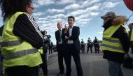 French Government's spokesperson Benjamin Griveaux (C) speaks with yellow vests (gilets jaunes) protestors before an official visit of Copelectronic, a company specialised in electronic and electric components, in Mouguerre, southwestern France, on Novemb