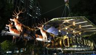 A hanging restaurant being raised by a crane in Kuala Lumpur inspired by Santa Claus travelling on a sleigh with reindeers for a Christmas season promotion on December 5, 2018.  AFP / Mohd Rasfan 