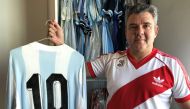 River Plate fanatic Javier Maluf poses with the jersey of Argentine striker Diego Maradona from the World Cup 1980 match between Argentina and England at his home in the Qatari capital, Doha on December 8, 2018. / AFP / FETHI BELAID 