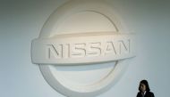 A woman walks under a Nissan logo at the company's headquarters in Yokohama on December 10, 2018. / AFP / Kazuhiro NOGI 