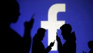 FILE PHOTO: Silhouettes of mobile users are seen next to a screen projection of Facebook logo in this picture illustration taken March 28, 2018. REUTERS/Dado Ruvic/Illustration