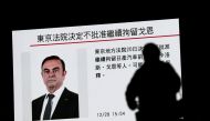A pedestrian walks past a television screen showing a news program featuring former Nissan chief Carlos Ghosn in Tokyo on December 20, 2018.  AFP / Behrouz MEHRI

