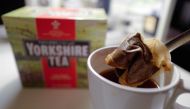 A man poses making a cup of tea with a Yorkshire Tea teabag with a box of tea in the background arranged as an illustration in London on December 19, 2018.  AFP / Tolga Akmen
 