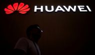 FILE PHOTO: A man walks past a sign board of Huawei at CES (Consumer Electronics Show) Asia 2018 in Shanghai, China June 14, 2018. REUTERS/Aly Song/File Photo/File Photo