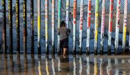 A girl from Salvador, part of the Central American migrants hoping to reach the United States, looks through the US-Mexico border fence in Playas de Tijuana, Baja California State, Mexico, on December 29, 2018.  AFP / GUILLERMO ARIAS
