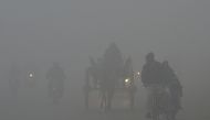 Pakistani commutes drive their vehicles on a road amid heavy fog and smog conditions in Lahore on January 3, 2019.  AFP / ARIF ALI