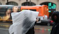 A woman covers her head with plastic as rain falls in Hollywood, California January 14, 2019. AFP / Robyn Beck