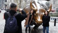People pose for photos with the Charging Bull or Wall Street Bull in the Manhattan borough of New York City,  January 16, 2019. Reuters/Carlo Allegri