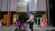A woman walks outside of a fashion store in Beijing on January 21, 2019.  AFP / NICOLAS ASFOURI