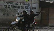 A riot policeman on a motorcycle points his gun during clashes with anti-government demonstrators in the neighborhood of Los Mecedores, in Caracas, on January 21, 2019. AFP / Federico Parra