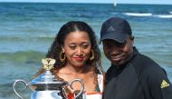 Japan's Naomi Osaka and her father Leonard Francois pose for photographs with the championship trophy at the Brighton Beach in Melbourne on January 27, 2019, a day after her victory against Czech Republic's Petra Kvitova in the women's singles final at th