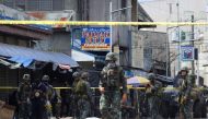Policemen and soldiers keep watch as body bags (in white), containing the remains of blast victims, as seen in a cordoned area outside a church in Jolo, Sulu province on the southern island of Mindanao, on January 27, 2019. AFP / Nickee Butlangan 