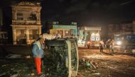 A man inspects a damaged car lying on its side in the tornado-hit Luyano neighborhood in Havana early on January 28, 2019. AFP / YAMIL LAGE